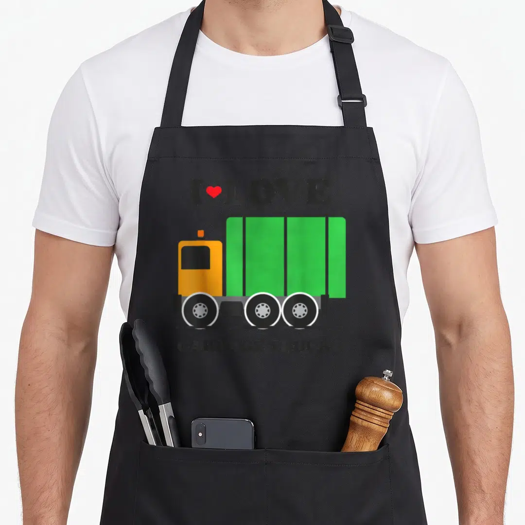 Vintage garbage truck apron - Cartoon green and yellow garbage truck with I Love Garbage Trucks text and red heart — shown on a black cotton canvas apron against a white background