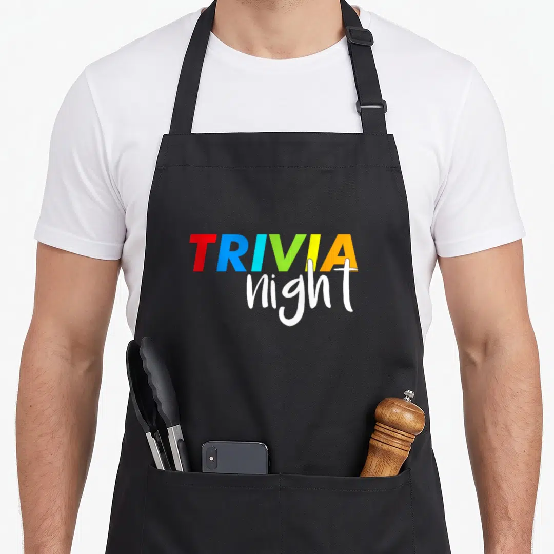 Trivia game aprons - Stacked TRIVIA night text in colorful block letters and white script — shown on a black cotton canvas apron against a white background