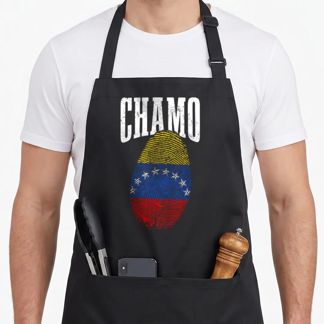 Chamo pride apron - Distressed white CHAMO text above a fingerprint patterned in Venezuelan flag colors yellow blue red — shown on a black cotton canvas apron against a white background