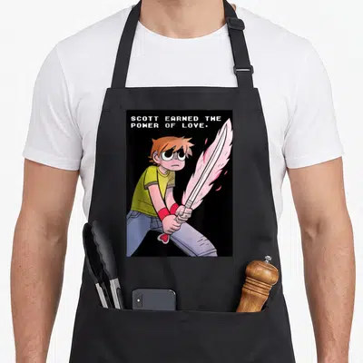 Earned pilgrim apron - Cartoon man holding pink energy sword below stacked white text SCOTT EARNED THE POWER OF LOVE — shown on a black cotton canvas apron against a white background