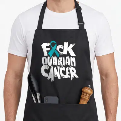Ovarian cancer awareness ribbon apron - White stacked text FUCK OVARIAN CANCER with teal ribbon replacing the U — shown on a black cotton canvas apron against a white background