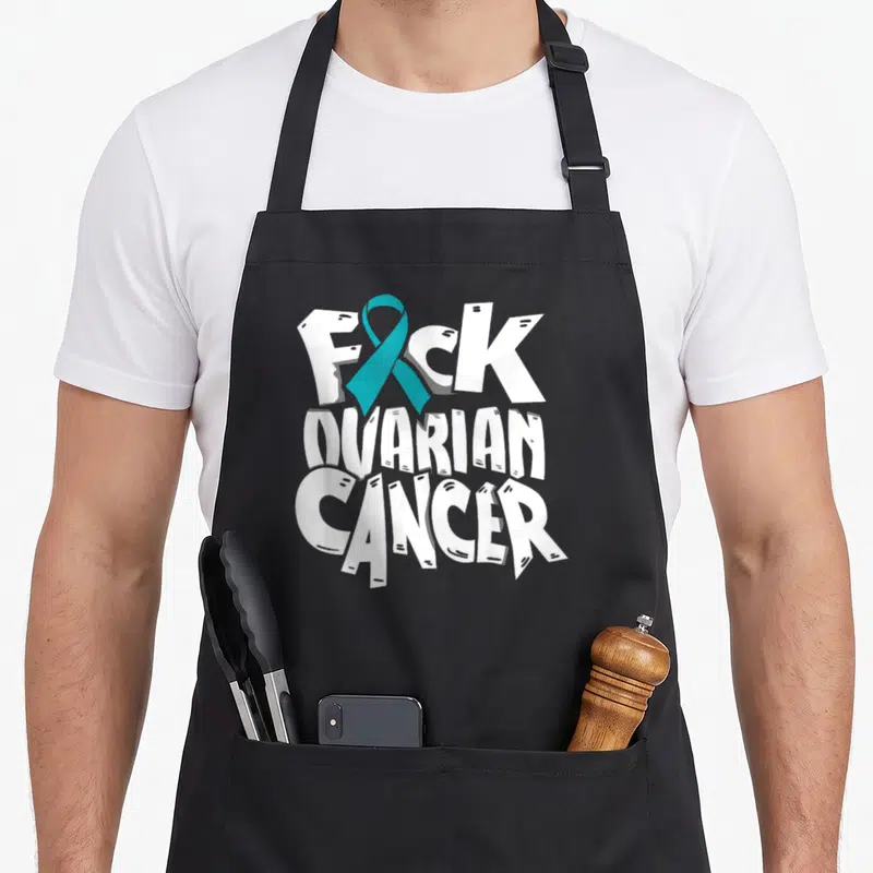 Ovarian cancer awareness ribbon apron - White stacked text FUCK OVARIAN CANCER with teal ribbon replacing the U — shown on a black cotton canvas apron against a white background