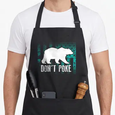 Poke superhero bear apron - White polar bear silhouette over teal distressed background with text DON'T POKE — shown on a black cotton canvas apron against a white background