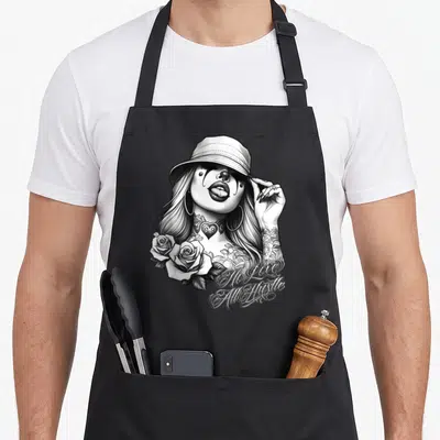 Hustle tattoo apron - Chicana clown woman with roses and No Love All Hustle text in black and white line art — shown on a black cotton canvas apron against a white background