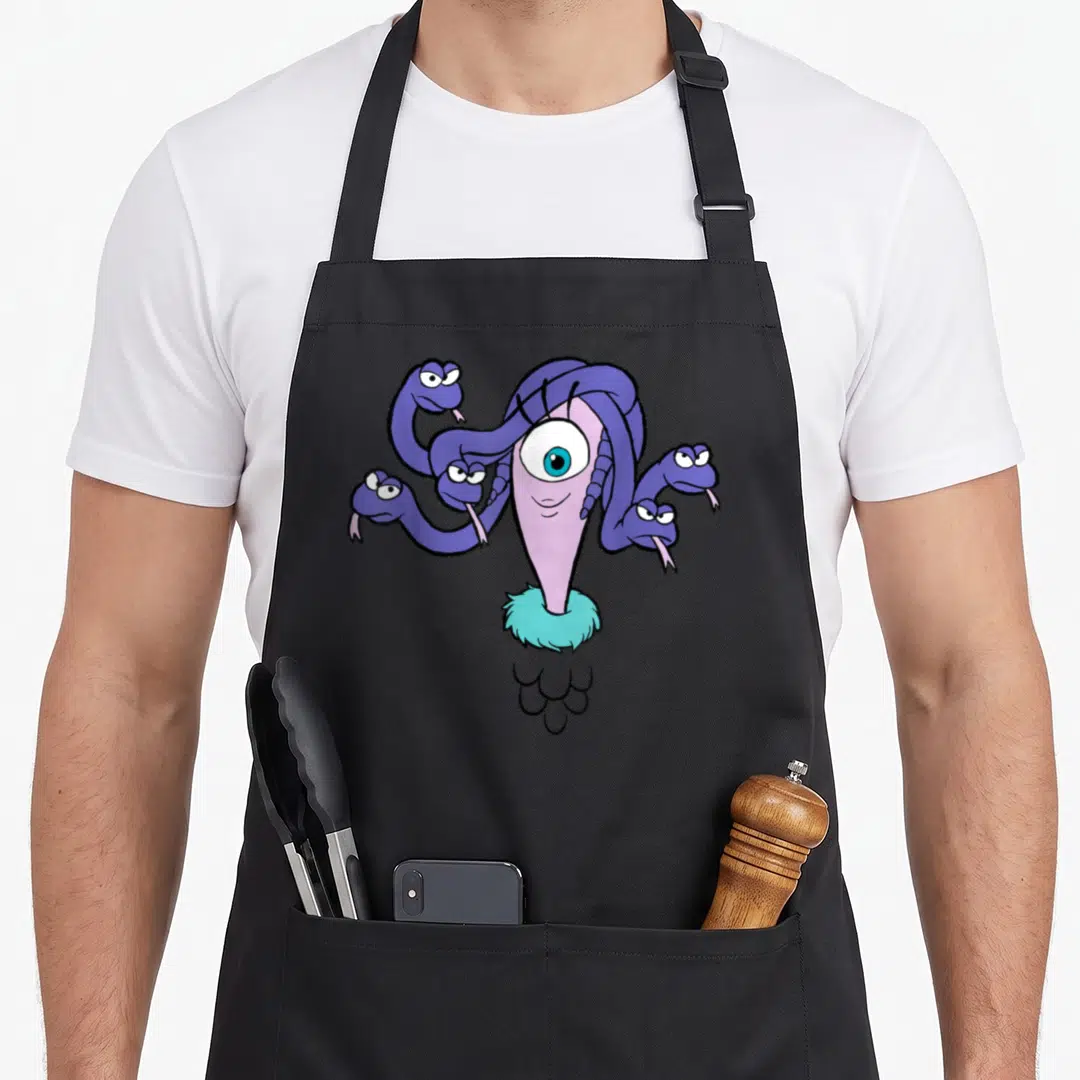 Celia face apron - Cartoon purple one-eyed monster with five snake heads, turquoise fur collar, white scales — shown on a black cotton canvas apron against a white background