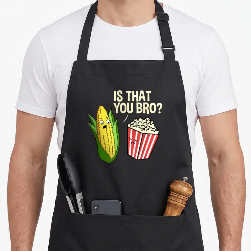 Bro hiking lover apron - Cartoon corn asks is that you bro to a red and white striped popcorn box — shown on a black cotton canvas apron against a white background