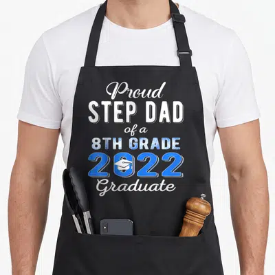 Step school dad apron - Stacked text reading Proud STEP DAD of a 8TH GRADE 2022 Graduate with a white cap inside — shown on a black cotton canvas apron against a white background