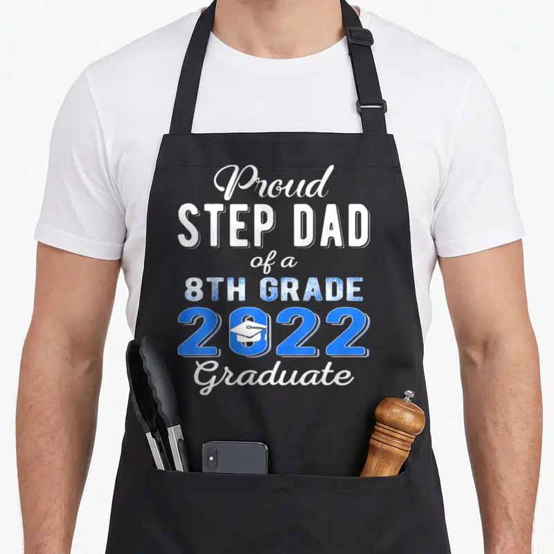 Step school dad apron - Stacked text reading Proud STEP DAD of a 8TH GRADE 2022 Graduate with a white cap inside — shown on a black cotton canvas apron against a white background