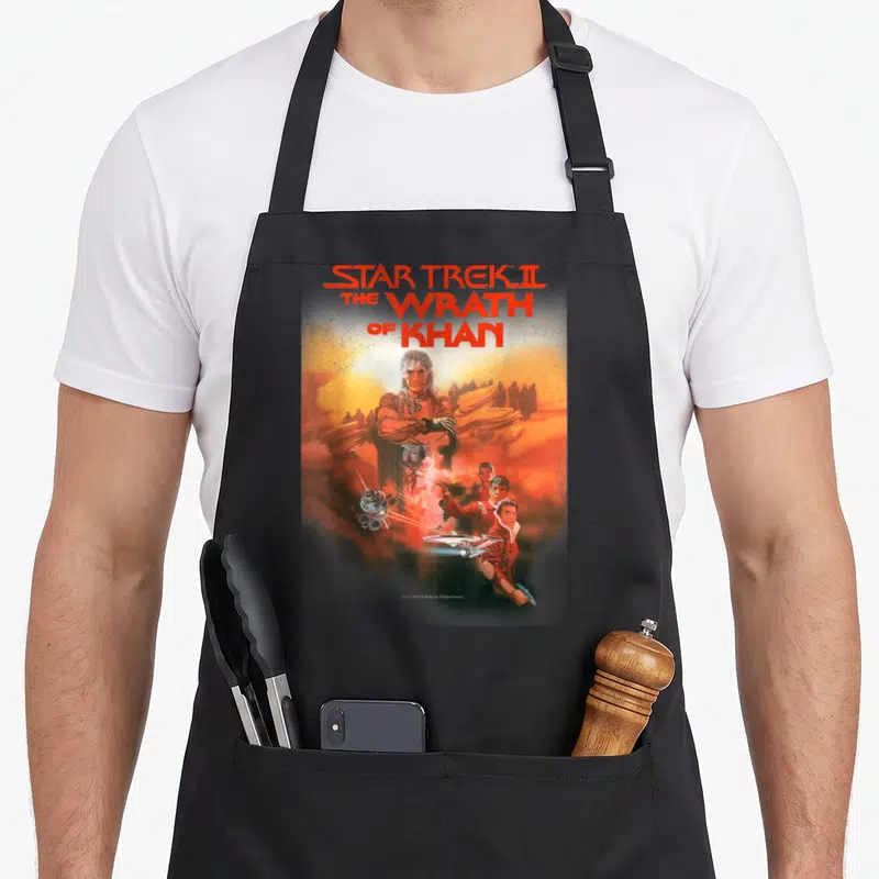 Wrath star apron - Star Trek II The Wrath of Khan movie poster art with Khan and spaceship in red orange yellow brown — shown on a black cotton canvas apron against a white background
