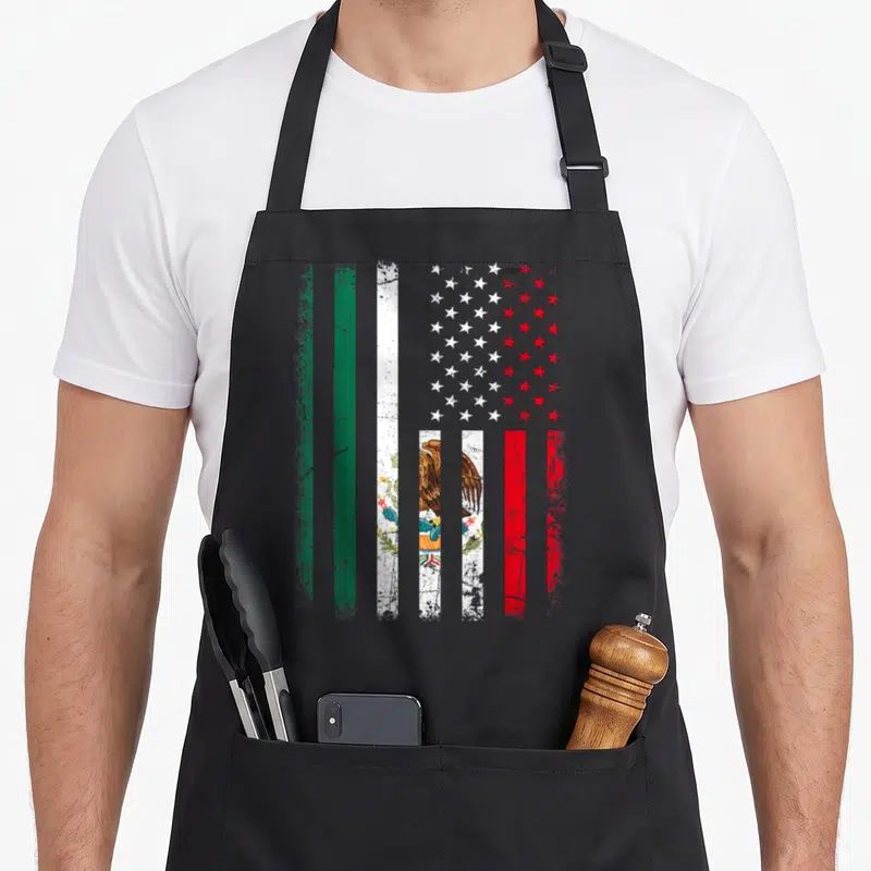Root mexico apron - Distressed hybrid flag with green white red stripes and blue stars centered with Mexican coat — shown on a black cotton canvas apron against a white background