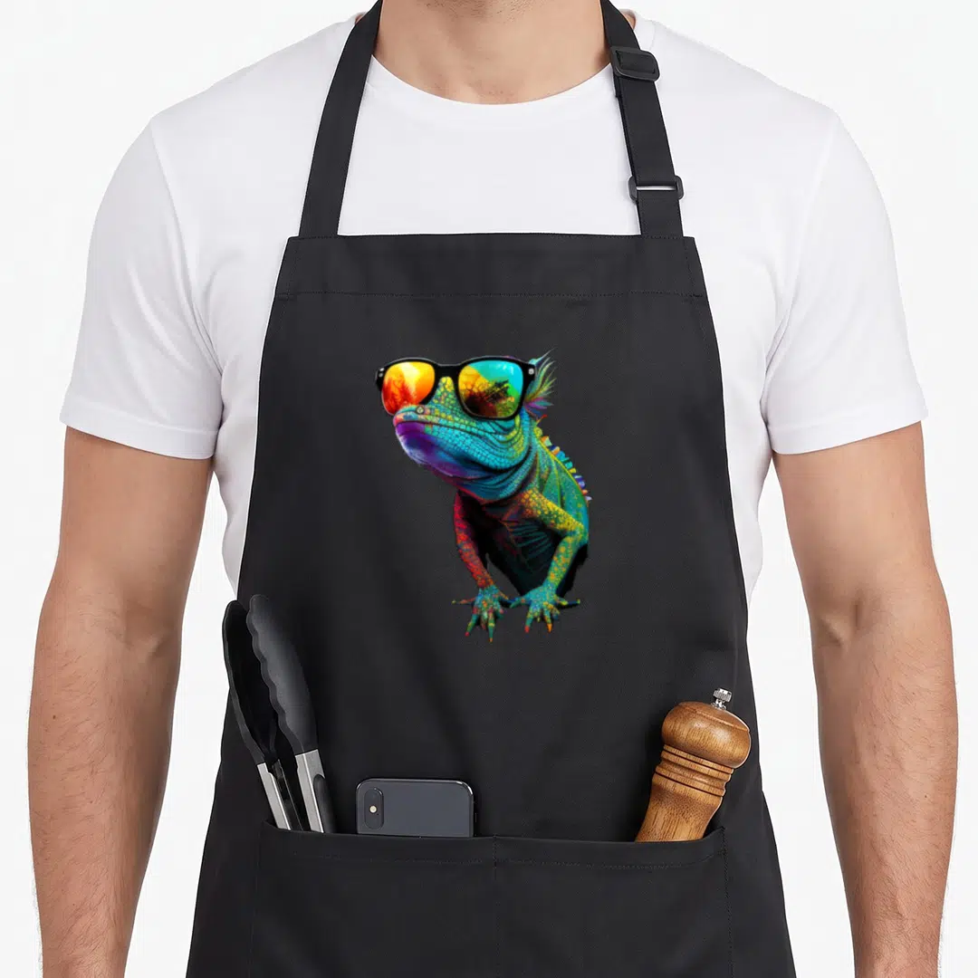 Lizard sunglasses funny apron - Rainbow colored iguana wearing black sunglasses in cartoon style — shown on a black cotton canvas apron against a white background