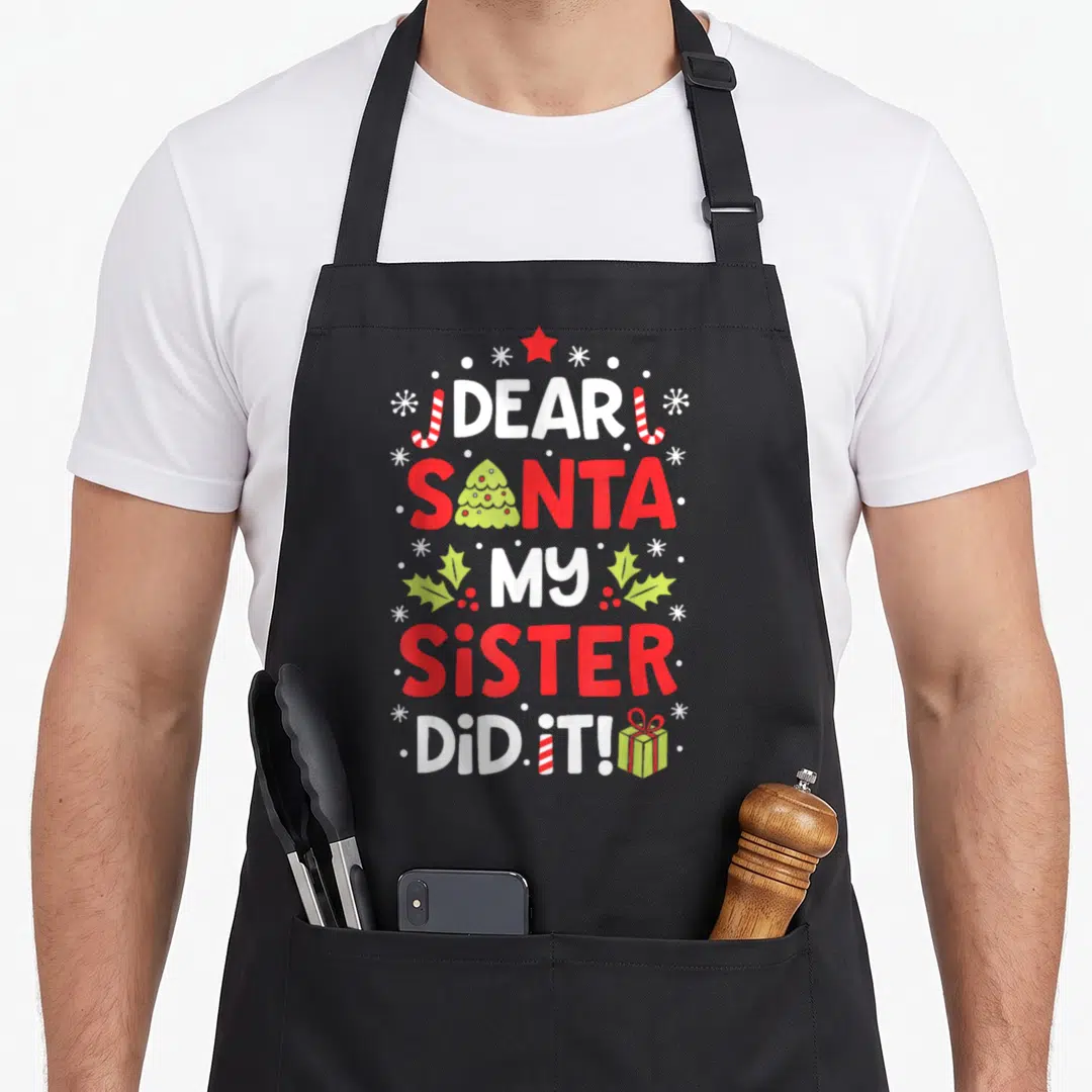 Sister christmas santa apron - Stacked text DEAR SANTA MY SISTER DID IT with tree, candy canes, holly, and gift box — shown on a black cotton canvas apron against a white background
