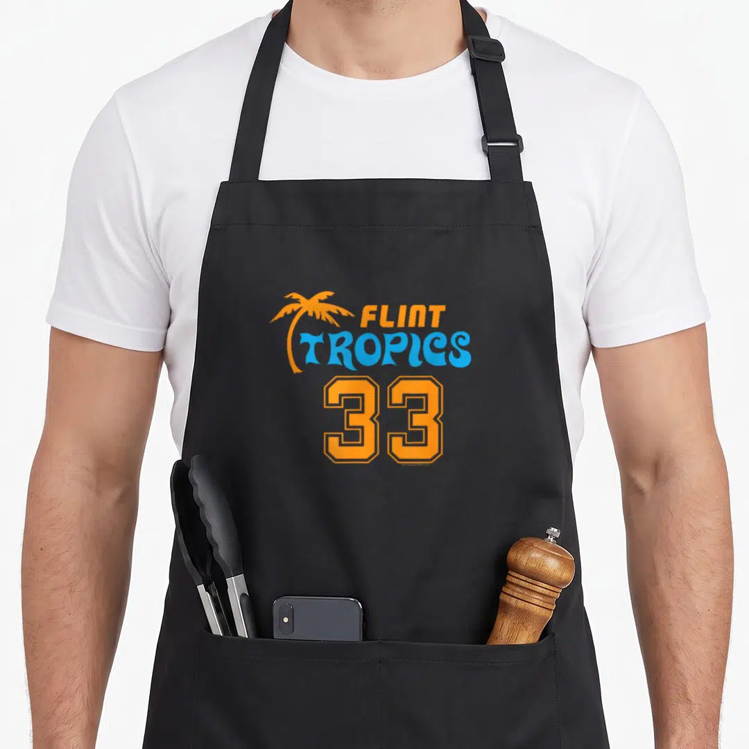 Semi pro apron - Orange palm tree next to Flint Tropics 33 text in blue and orange varsity font — shown on a black cotton canvas apron against a white background