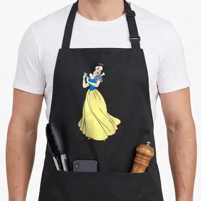 Snow princess apron - Cartoon Snow White in yellow dress and blue bodice with red bow — shown on a black cotton canvas apron against a white background