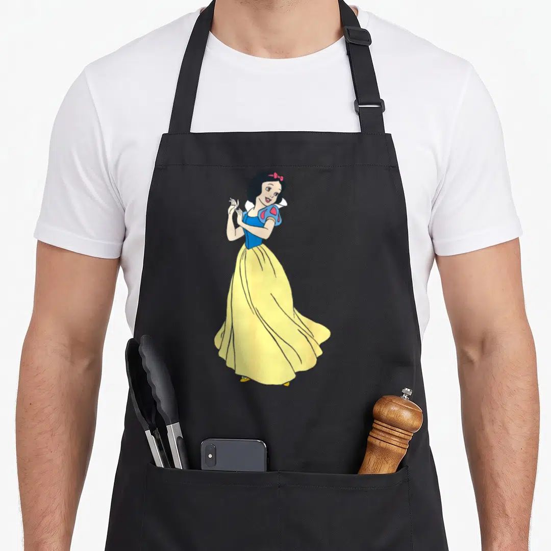 Snow princess apron - Cartoon Snow White in yellow dress and blue bodice with red bow — shown on a black cotton canvas apron against a white background