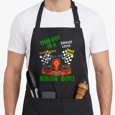 Motor racing apron - Cartoon go kart flanked by two checkered flags with colorful descriptive text — shown on a black cotton canvas apron against a white background