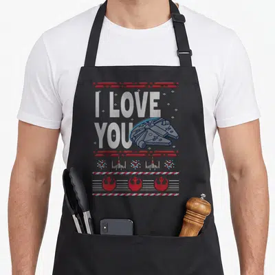 Ugly falcon apron - Knit-style I LOVE YOU text with Millennium Falcon and X-wing borders in white, red, and blue — shown on a black cotton canvas apron against a white background
