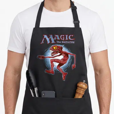 Monster magic apron - MAGIC The Gathering logo above a red goblin lunging in front of a blue swirl — shown on a black cotton canvas apron against a white background