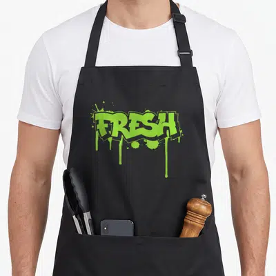 Fresh school apron - Lime green FRESH graffiti text with paint drips and splatters — shown on a black cotton canvas apron against a white background