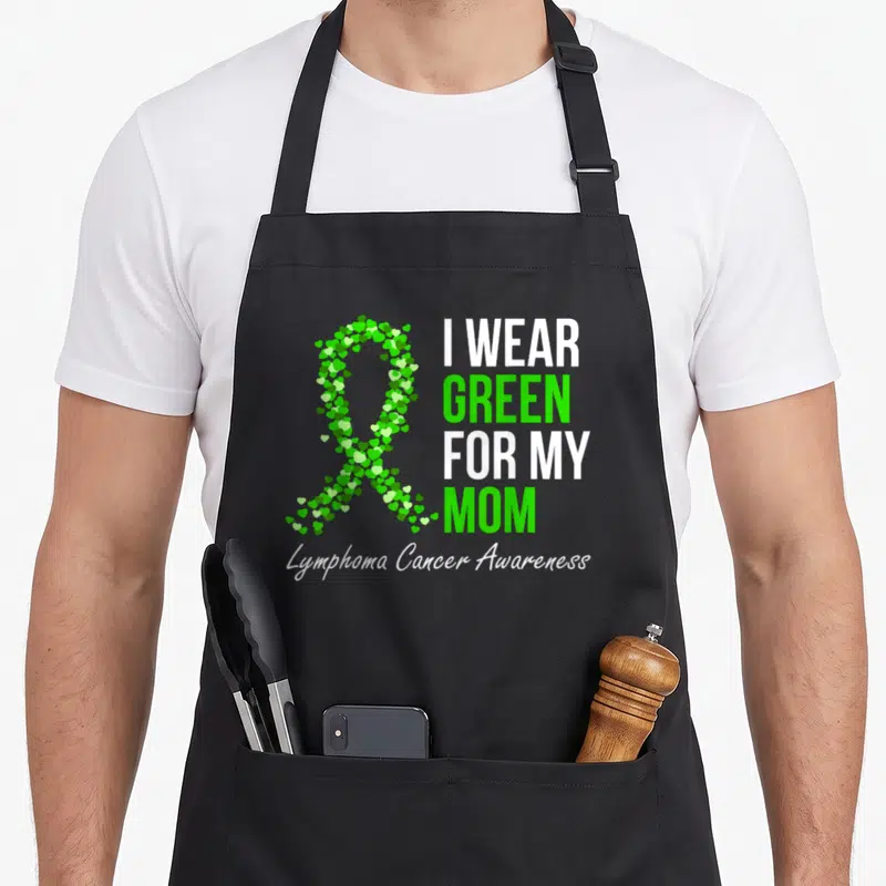Lymphoma cancer ribbon apron - Green heart awareness ribbon and I wear green for my mom text — shown on a black cotton canvas apron against a white background