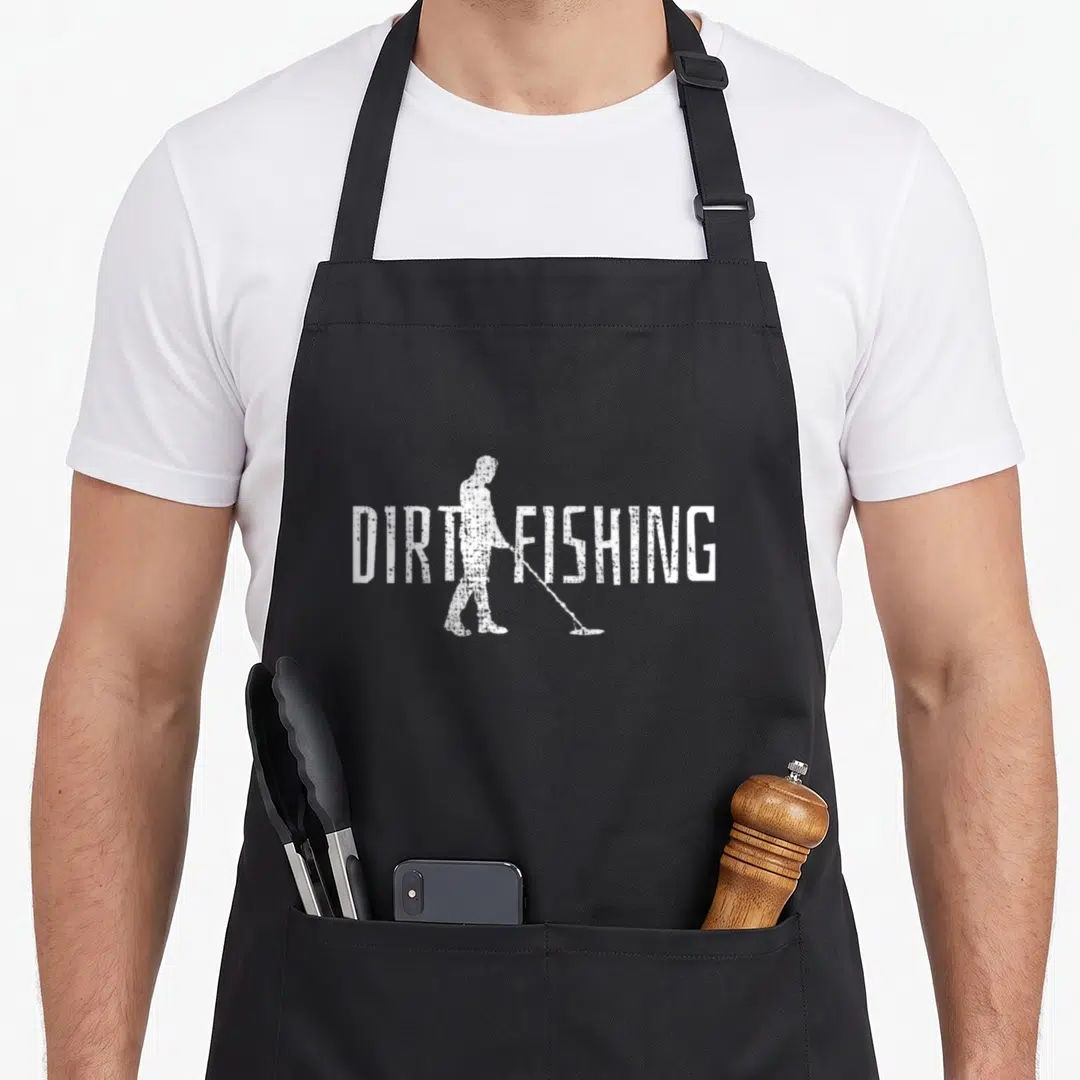 Detection metal detecting apron - White distressed DIRT FISHING text with a metal detectorist silhouette behind it — shown on a black cotton canvas apron against a white background
