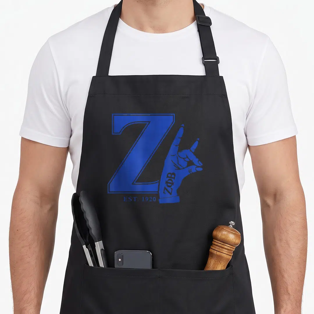 Est 1920s apron - Blue letter Z with hand making gesture and Greek letters ZΦΒ on wrist below EST 1920 — shown on a black cotton canvas apron against a white background
