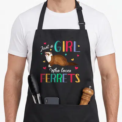 Funny animal i love my ferret apron - Cartoon ferret with Just a GIRL Who loves FERRETS text and scattered hearts — shown on a black cotton canvas apron against a white background
