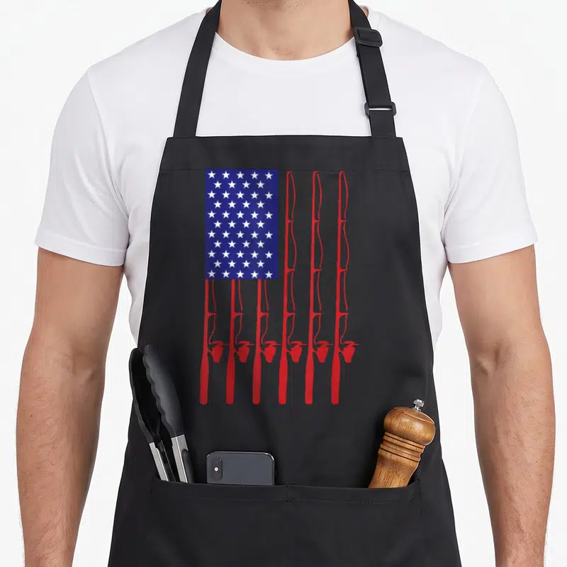 Flag fishing apron - Seven red fishing rods stand vertically under a blue rectangle filled with white stars — shown on a black cotton canvas apron against a white background