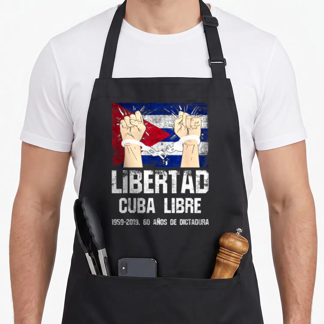 Libertad cuba apron - Two fists breaking handcuffs over flag with 1959-2019 60 Años De Dictadura text — shown on a black cotton canvas apron against a white background