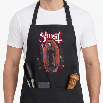 Luna ghost apron - Papa Emeritus surrounded by ghouls under an arched Ghost logo in cartoon style — shown on a black cotton canvas apron against a white background