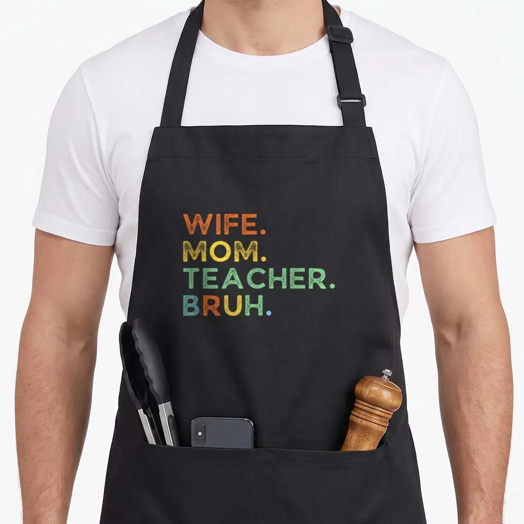 Wife bruh best teacher apron - Stacked WIFE MOM TEACHER BRUH text in orange yellow green blue distressed font — shown on a black cotton canvas apron against a white background