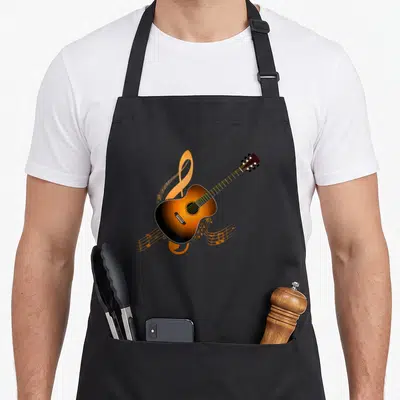 Musician acoustics apron - Diagonal acoustic guitar over orange treble clef and musical notes in brown and black — shown on a black cotton canvas apron against a white background