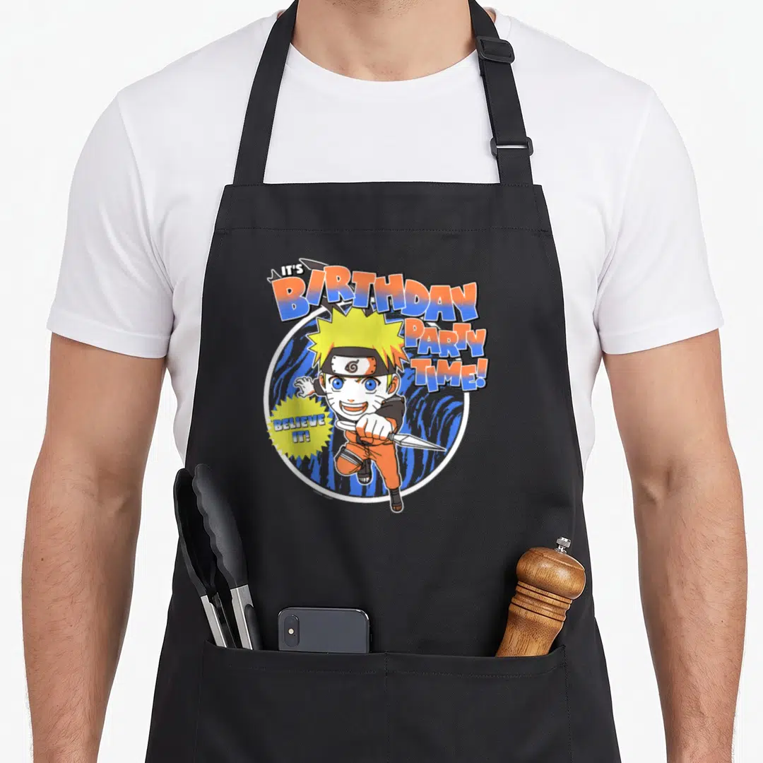 Shippuden birthday anime mom apron - Naruto holding kunai with IT'S BIRTHDAY PARTY TIME! and BELIEVE IT! text in orange — shown on a black cotton canvas apron against a white background