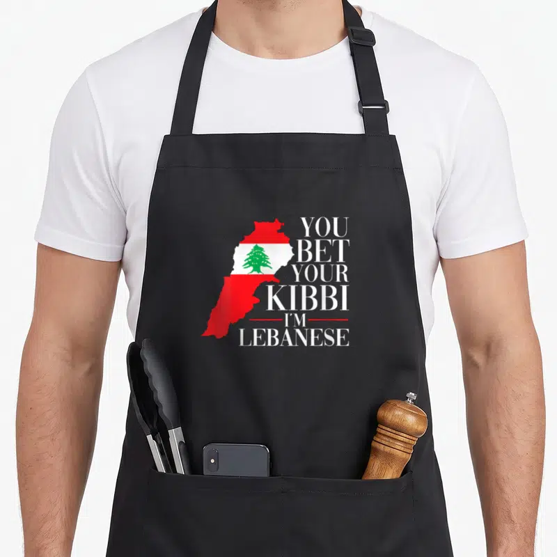 Bet lebanon apron - Lebanon map filled with red white green flag next to stacked white text — shown on a black cotton canvas apron against a white background