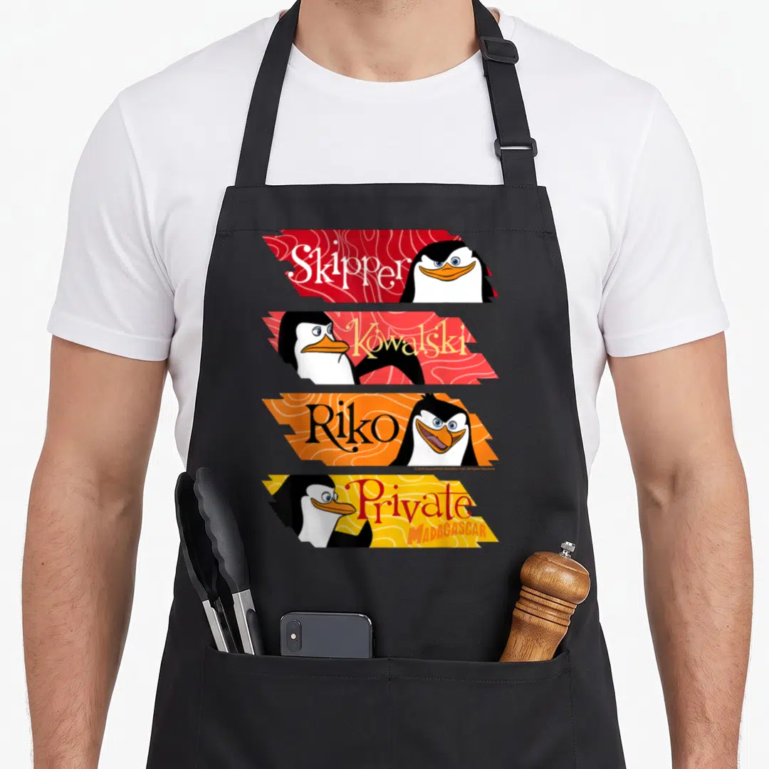 Panel penguin aprons - Four stacked banners with penguin faces and names Skipper Kowalski Riko Private in red orange — shown on a black cotton canvas apron against a white background