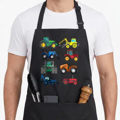 Tractor combine apron - Eight cartoon tractors and farm vehicles in green, yellow, red, blue, and orange arranged — shown on a black cotton canvas apron against a white background