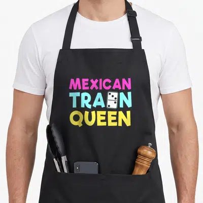 Train mexican apron - Stacked pink blue and yellow text reading MEXICAN TRAIN QUEEN with a white domino tile replacing — shown on a black cotton canvas apron against a white background