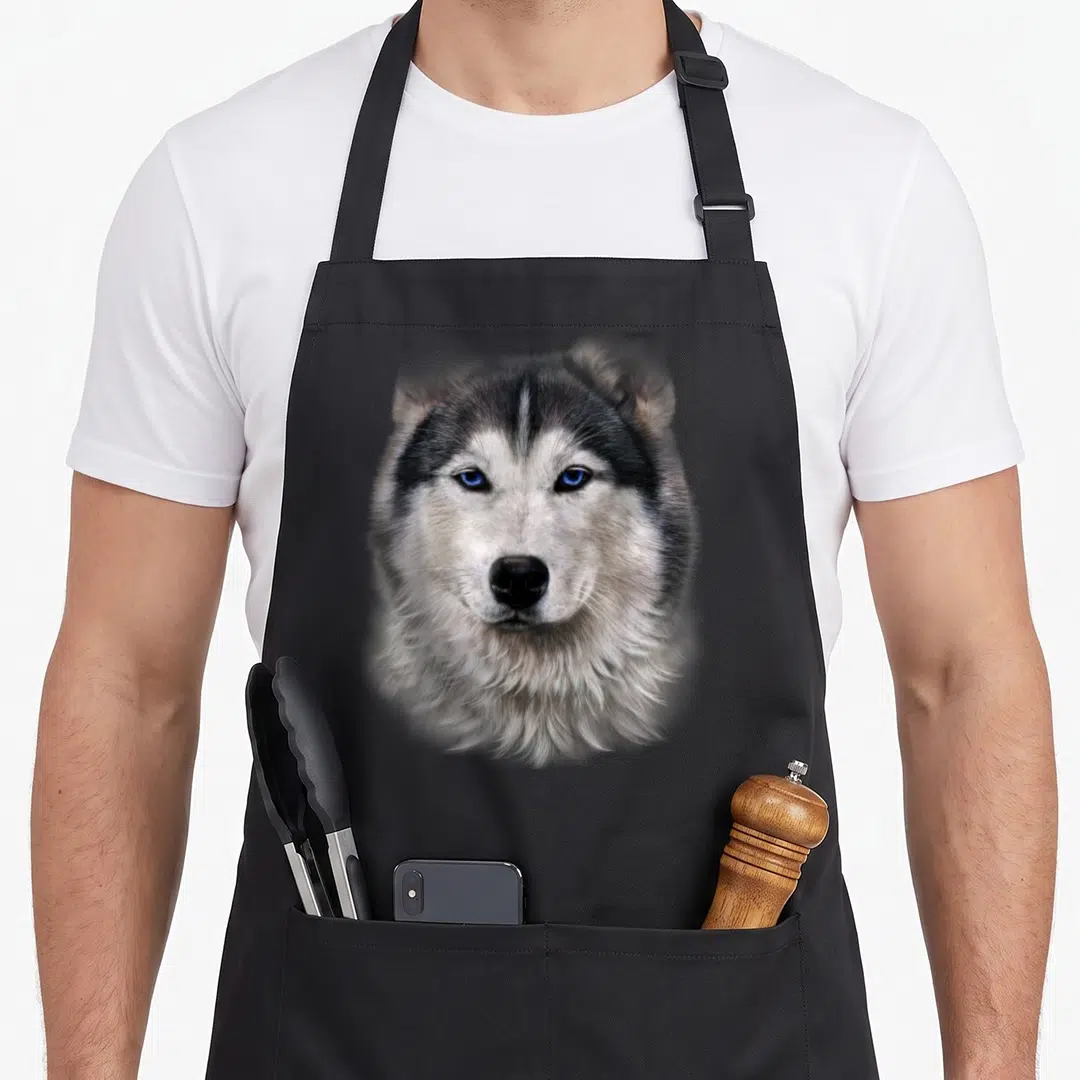Eyed dog apron - Realistic husky head portrait with blue eyes, grey white and black fur — shown on a black cotton canvas apron against a white background