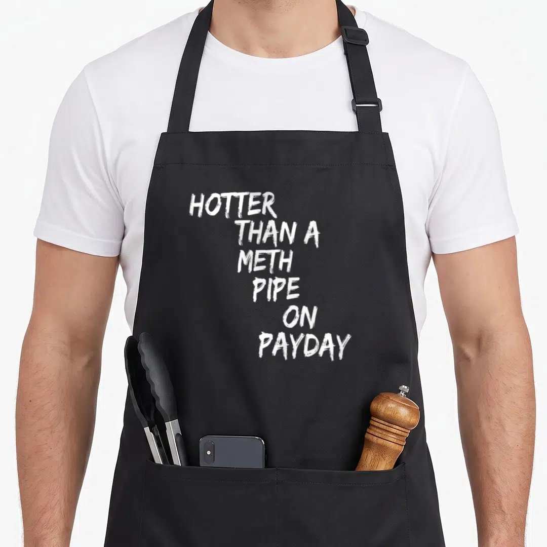 Hotter pipe apron - White stacked text reading HOTTER THAN A METH PIPE ON PAYDAY on black fabric — shown on a black cotton canvas apron against a white background