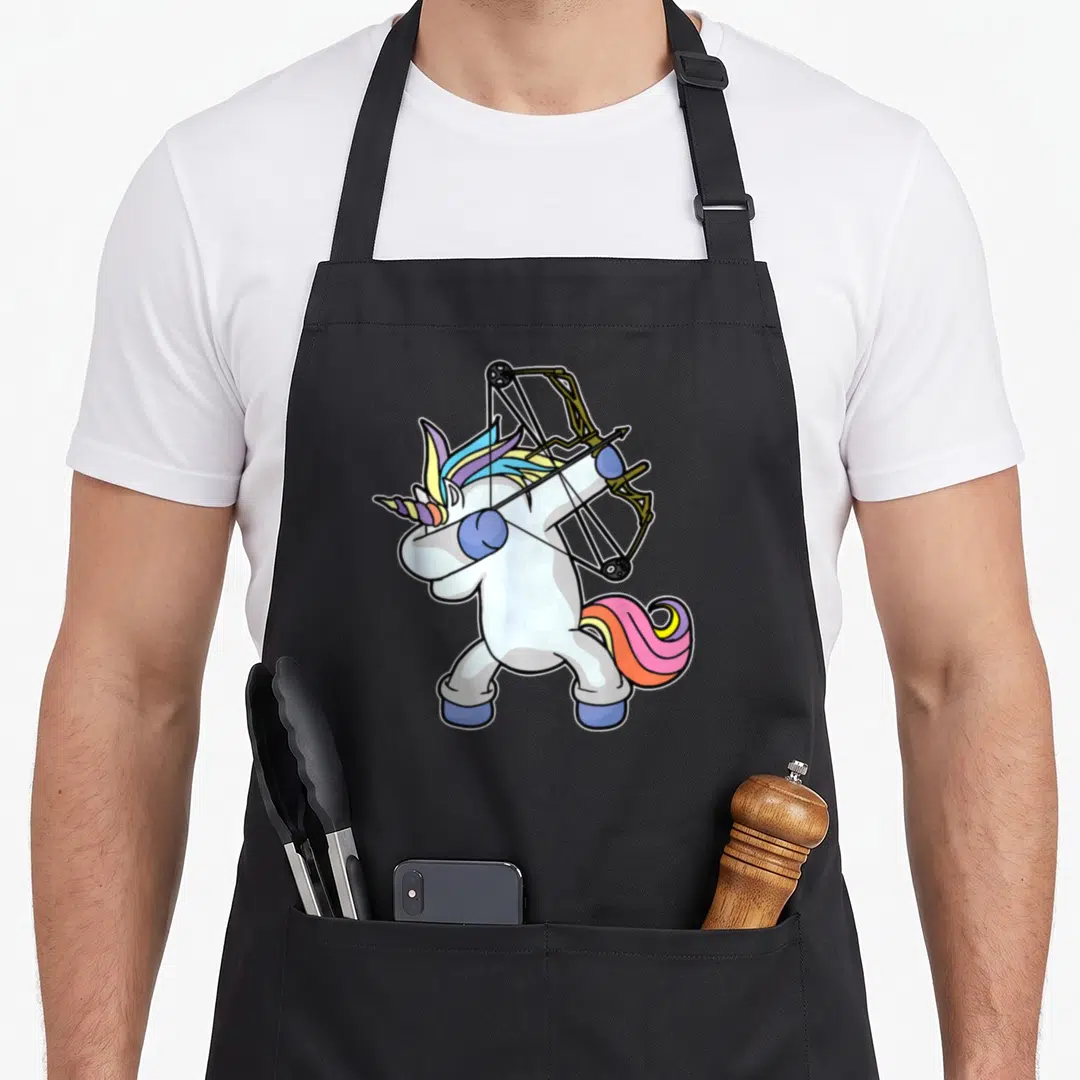Dabbing bow apron - White unicorn standing holding compound bow with rainbow mane in cartoon style — shown on a black cotton canvas apron against a white background