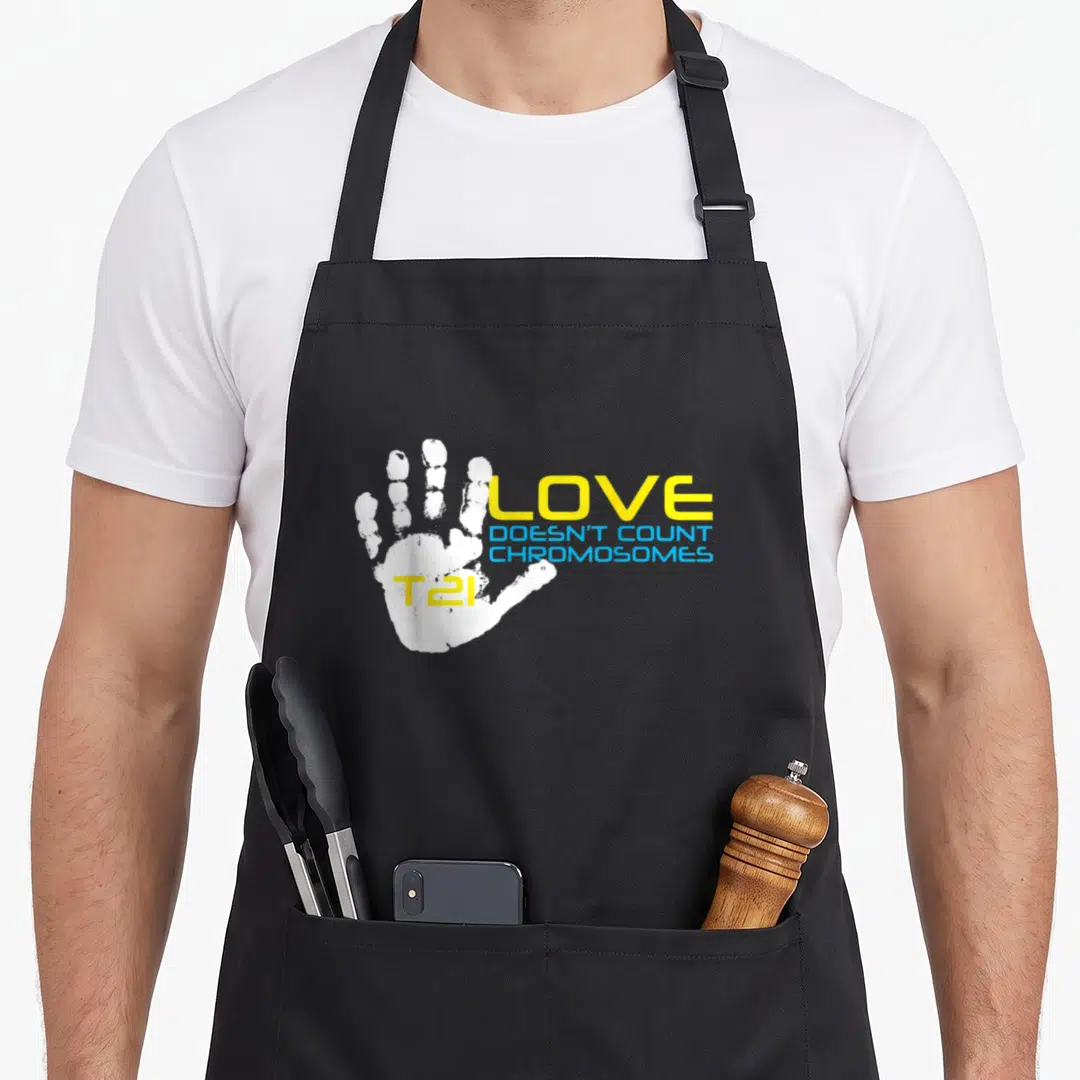 T21 chromosomes apron - White handprint with yellow LOVE and blue text on gray background — shown on a black cotton canvas apron against a white background