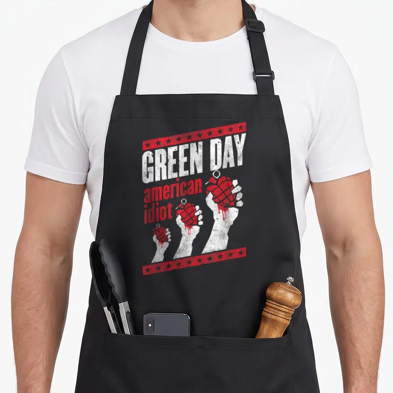 Funny hand apron - Three white hands holding red grenades with stacked Green Day American Idiot text and star borders — shown on a black cotton canvas apron against a white background