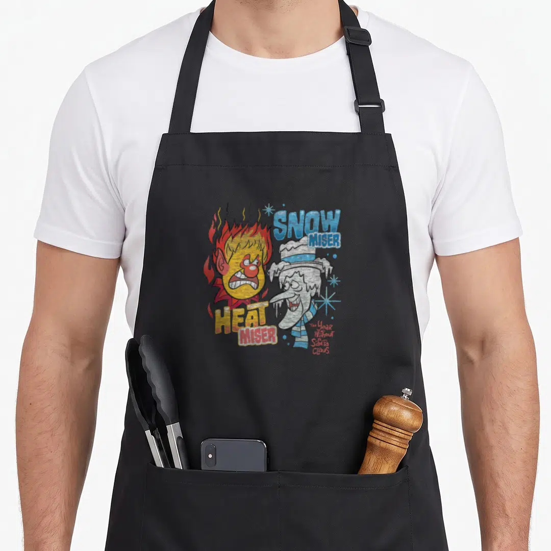 Heat snow white apron - Cartoon Heat and Snow Miser faces with red flames, blue snowflakes, and vertical script text — shown on a black cotton canvas apron against a white background