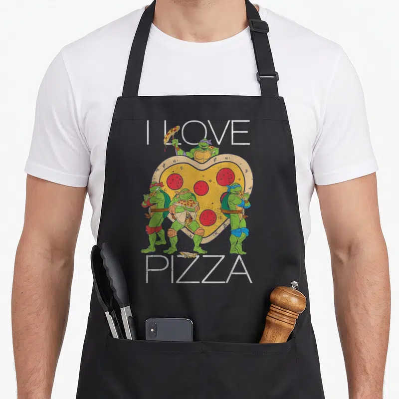 Vintage pizza apron - Four green turtles surrounding a heart-shaped pizza with I LOVE PIZZA text — shown on a black cotton canvas apron against a white background