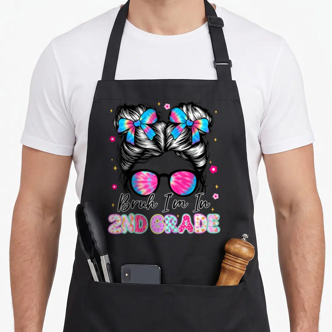 2nd messy aprons - Girl with messy buns tie-dye sunglasses and 2nd grade text — shown on a black cotton canvas apron against a white background