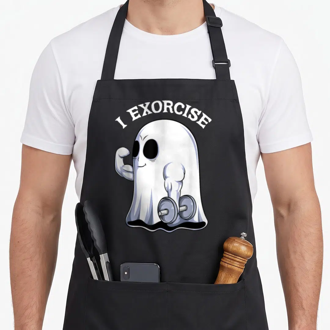 Exorcise halloween apron - Cartoon ghost holding dumbbell flexing arm with I EXORCISE text arched above — shown on a black cotton canvas apron against a white background