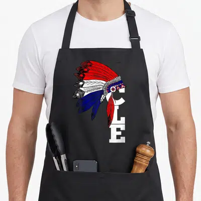 Iroqio cleveland apron - Cartoon headdress in red white blue feathers overlapping vertical white CLE letters — shown on a black cotton canvas apron against a white background