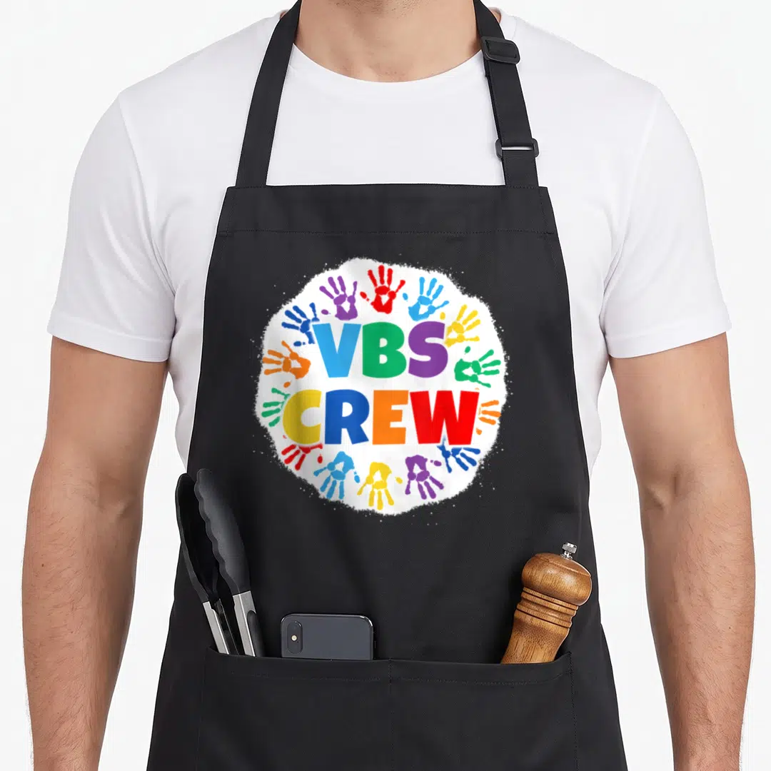 Vacation handprint apron - VBS CREW text surrounded by blue green purple yellow orange red handprints on white splatter — shown on a black cotton canvas apron against a white background
