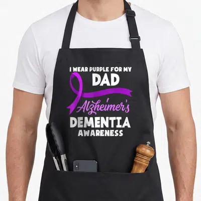 Dementia awareness alzheimer's aprons - Purple ribbon overlapping white text I WEAR PURPLE FOR MY DAD Alzheimer's — shown on a black cotton canvas apron against a white background