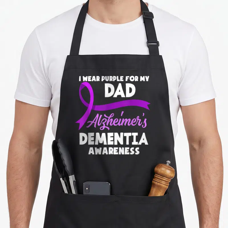 Dementia awareness alzheimer's aprons - Purple ribbon overlapping white text I WEAR PURPLE FOR MY DAD Alzheimer's — shown on a black cotton canvas apron against a white background
